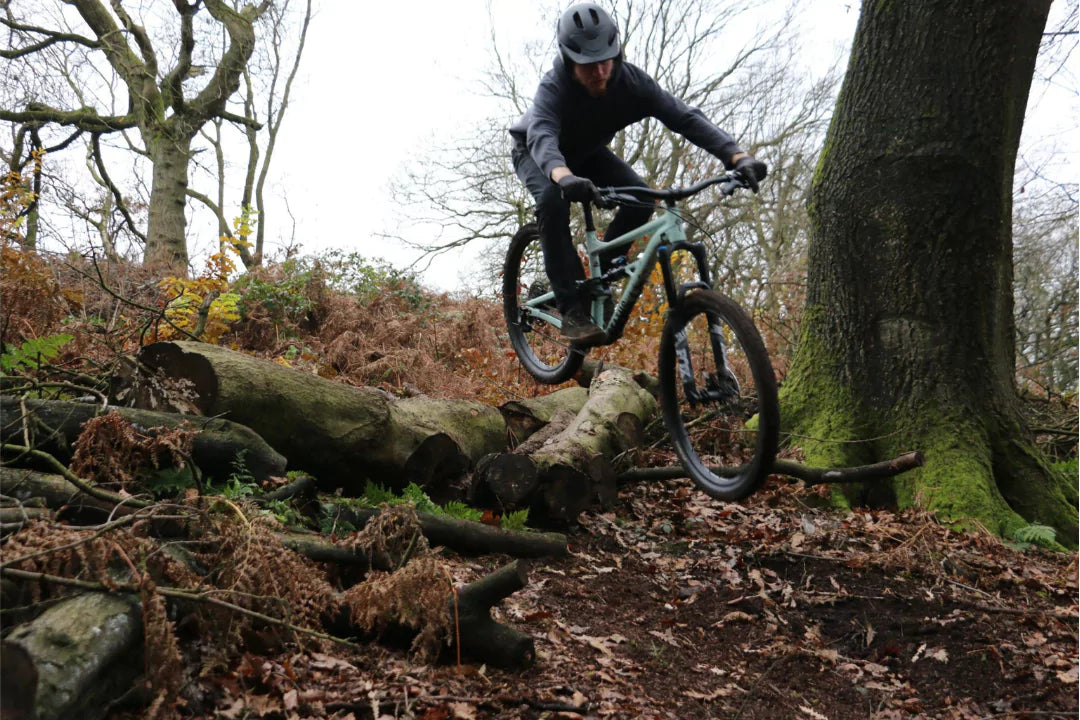 A man on a mountain bike jumping over a stump